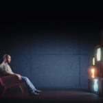 Caucasian man with glasses sitting on an armchair watching several vintage televisions broadcasting different programs. Concept of alienation, dependence on the mass media. Solitude.